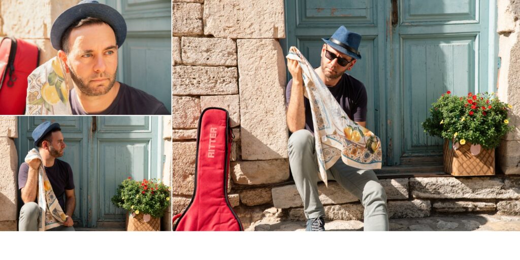 Ζευγάρι σε prewedding φωτογράφιση μπροστά από παλιά ξύλινη πόρτα, η νύφη με vintage γυαλιά και ο γαμπρός με κιθάρα στην πλάτη